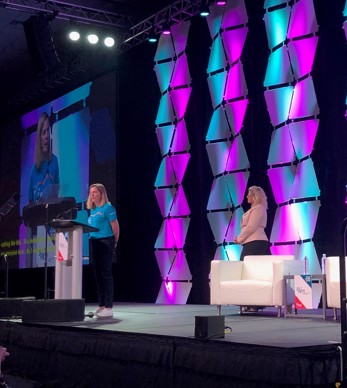 women stood on stage speaking at podium