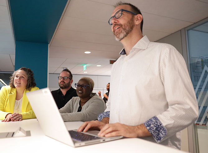 Group Of Colleagues On Laptop And Looking At A Presentation Together